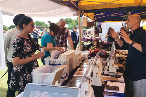 people browsing through wildlife prints at an outdoor event with Ashley Vincent