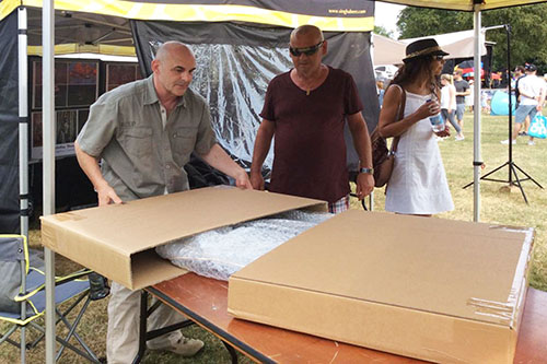 photographer Ashley Vincent boxing up a large wildlife picture at an outdoor event while the customers watch