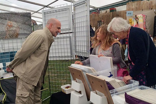 wildlife photographer Ashley Vincent talking to a granddaughter and grandmother at an outdoor event as they look through his pictures