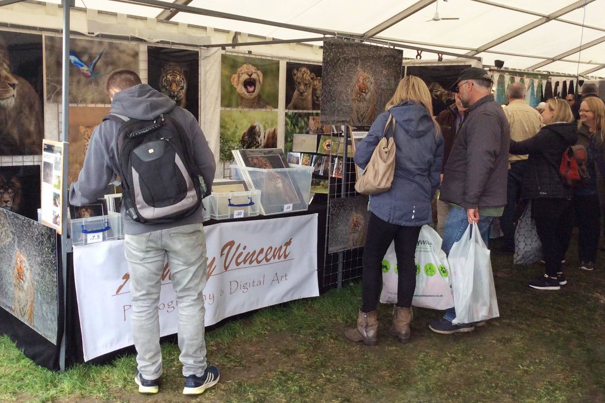 event stand of wildlife photographer Ashley Vincent with a couple taking to the photographer while another man looks through prints