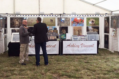 wildlife photographer Ashley Vincent talking talking with a customer in front of event stand