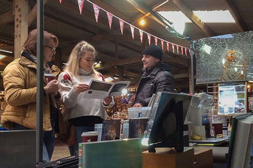 two ladies looking through a brochure at photographer Ashley Vincent’s event stand