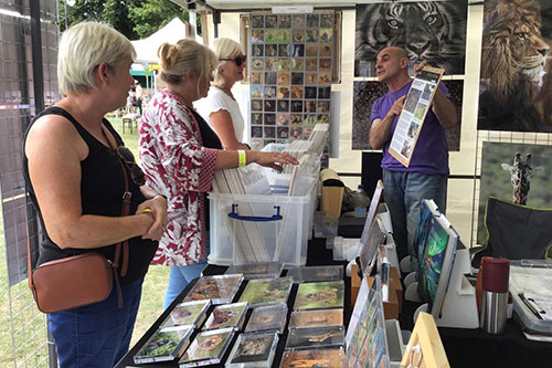ladies engaging with Ashley Vincent at his picture display stand at an event in Chichester