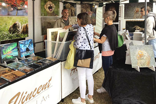 people engaging with Ashley Vincent at his picture display stand at an event in Hythe