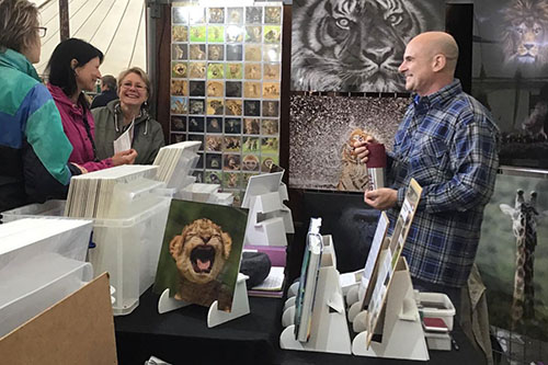 ladies engaging with Ashley Vincent at his picture display stand at the Rockingham Castle event