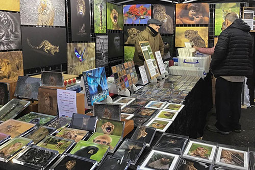 customers engaging with Ashley Vincent at his picture display gazebo at the Bury St Edmonds Christmas Fayre