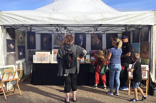 customers engaging with wildlife photographer ashley vincent at his stand at the high summer Eastbourne market
